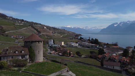 toma aérea giratoria de una antigua bodega de castillo en lutry, suiza con el lago de ginebra y los alpes suizos en la distancia