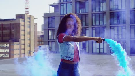 fashionable young woman on urban rooftop using a smoke grenade