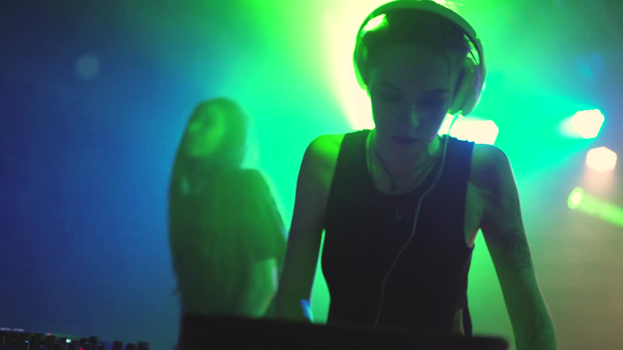 dos hermosas mujeres jóvenes dj tocan la música en la consola de mezcla en el club nocturno