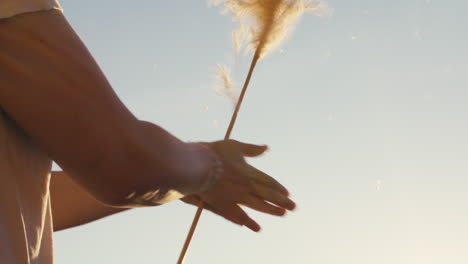 close-up shot of a young woman spinning pampas grass in her hands under the sunlight