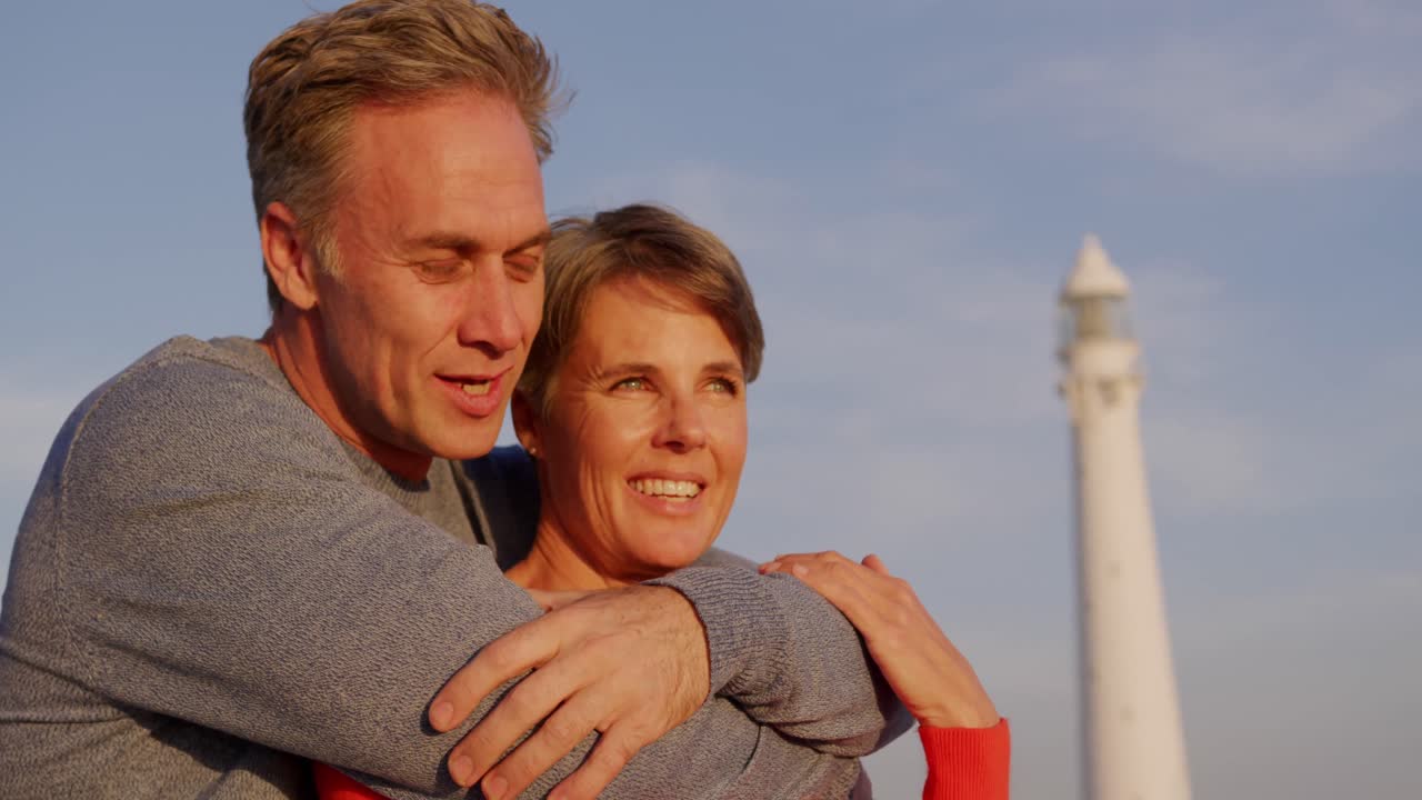 등대 근처 의 바다 에서 포옹 하는 부부