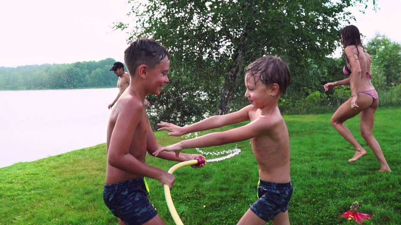 아버지 와 두 자녀 와 함께 잔디 ⁇  에서 놀면서 물 을  ⁇ 고 웃고 놀이터 에서 재미 를 즐기고 있으며, 호수 근처 에 있는 집 의 배경 에 잔디 ⁇  이 있다