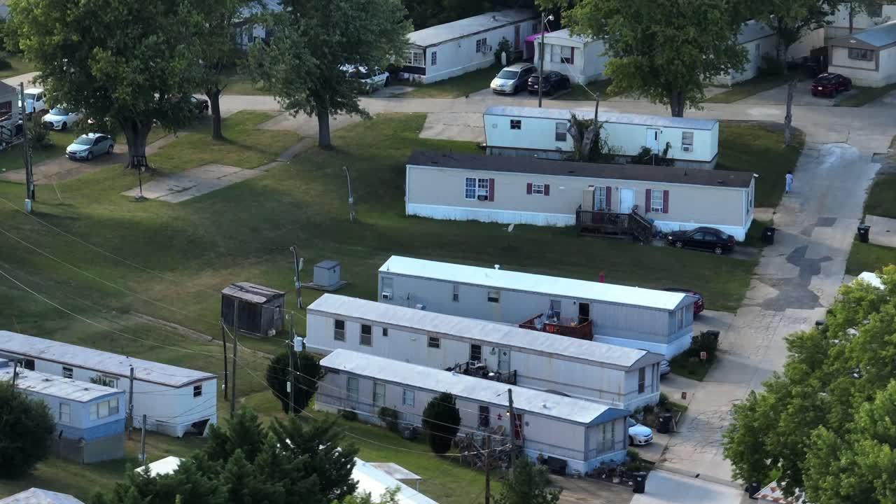 Dense populated small American mobile trailer homes in suburbia. Dusk scene in summer. Aerial view. Old rusty and tiny houses for less rent in USA
