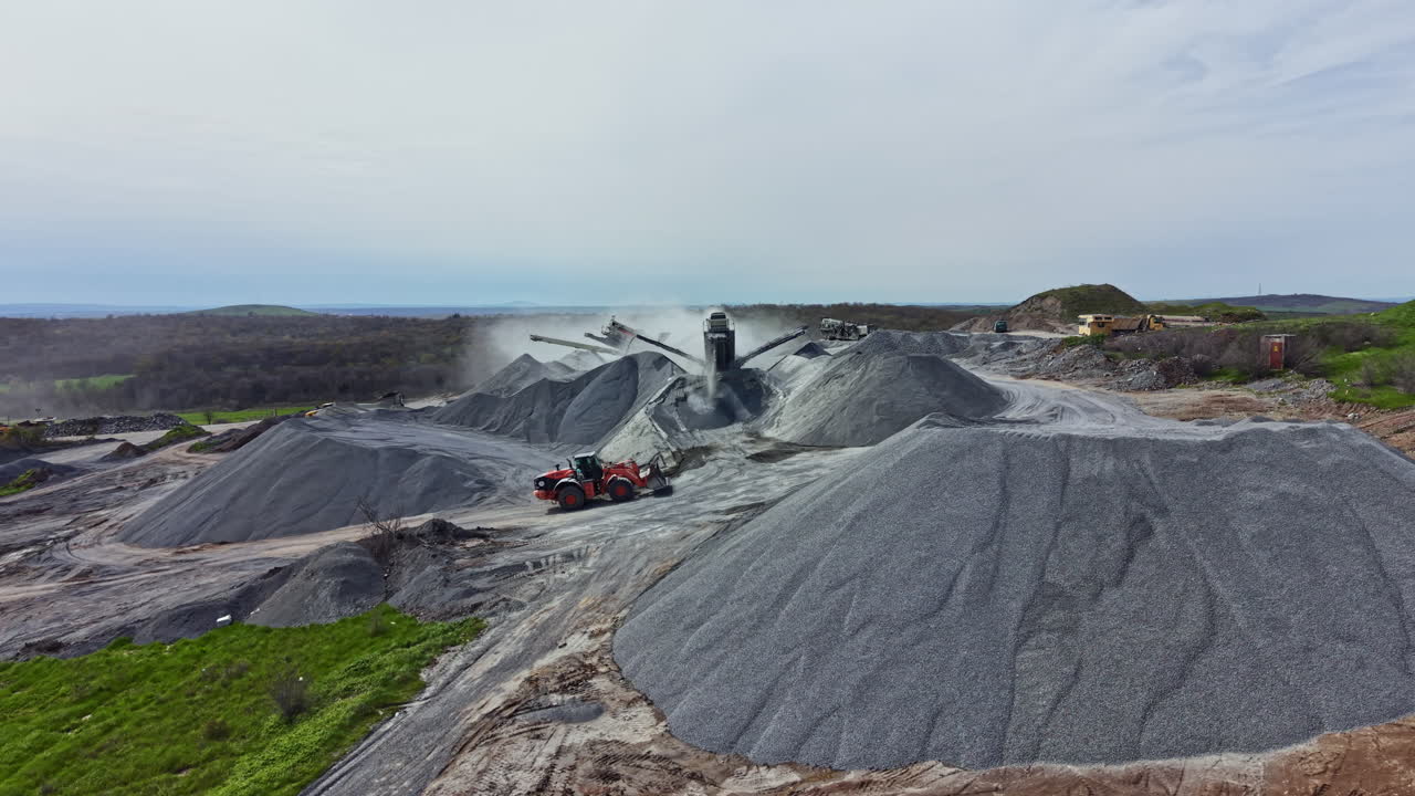 Pekerja dan mesin beroperasi di lokasi tambang granit di siang hari, mengekstraksi batu untuk proyek bangunan dan konstruksi di daerah pedesaan.