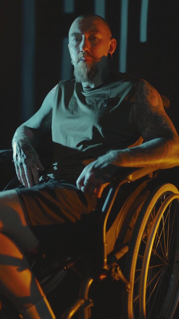 Man in wheelchair moves in dimly lit space with unique lighting effects during evening hours