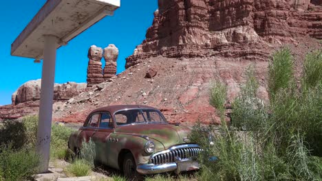 an old car sits at am abandoned gas station along a rural highway in utah