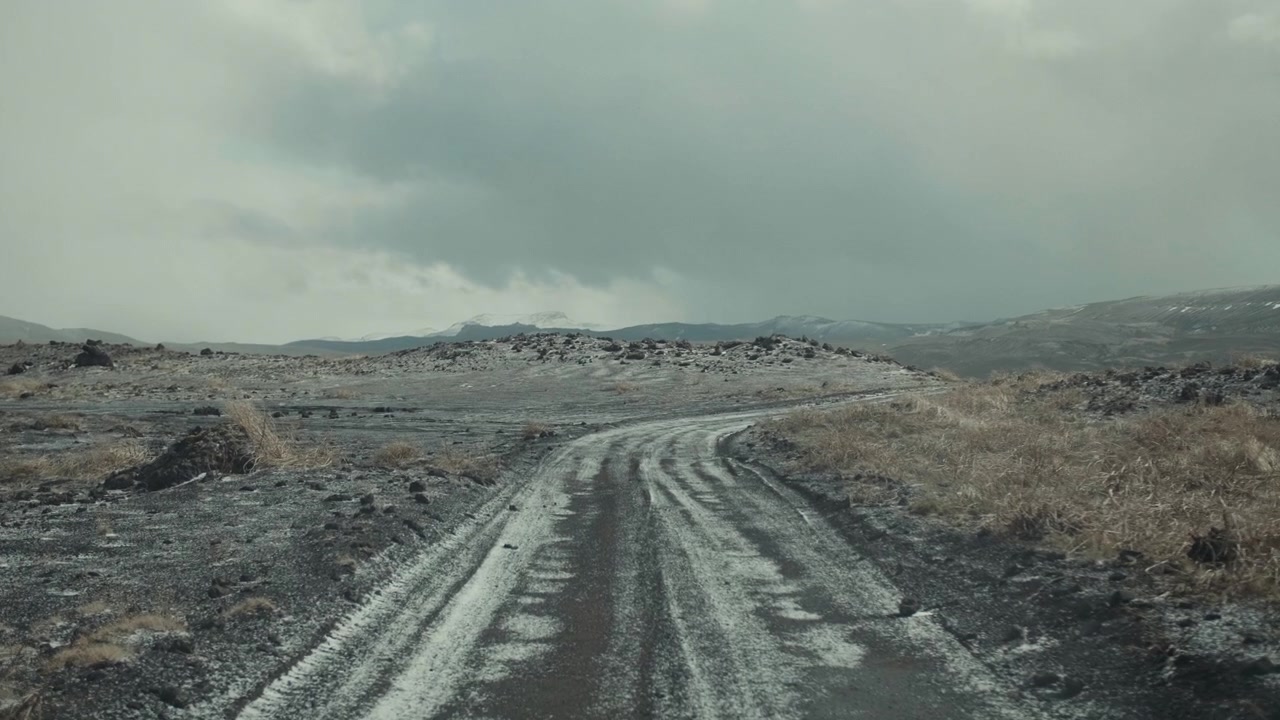 Remote Dirt Road Covered in Snow Through a Barren Winter Landscape