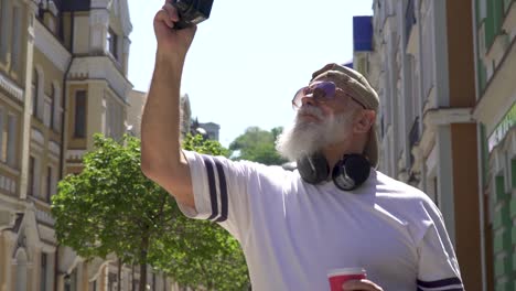 stylish mature man in sunglasses take photo in the city