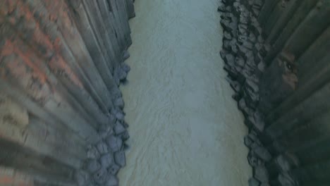 aerial: vista de arriba hacia abajo del cañón del río studlagil con columnas de basalto en el noreste de islandia