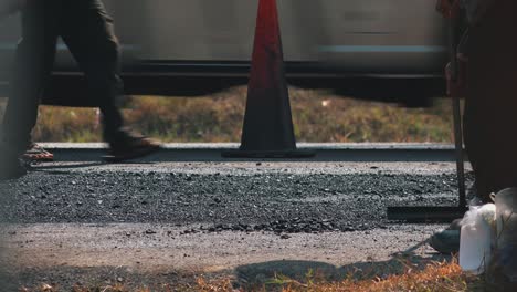 Nahaufnahme-Von-Bauarbeitern,-Die-Manuell-Eine-Neu-Verlegte-Straßenoberfläche-Für-Die-Dampfwalze-Ebnen