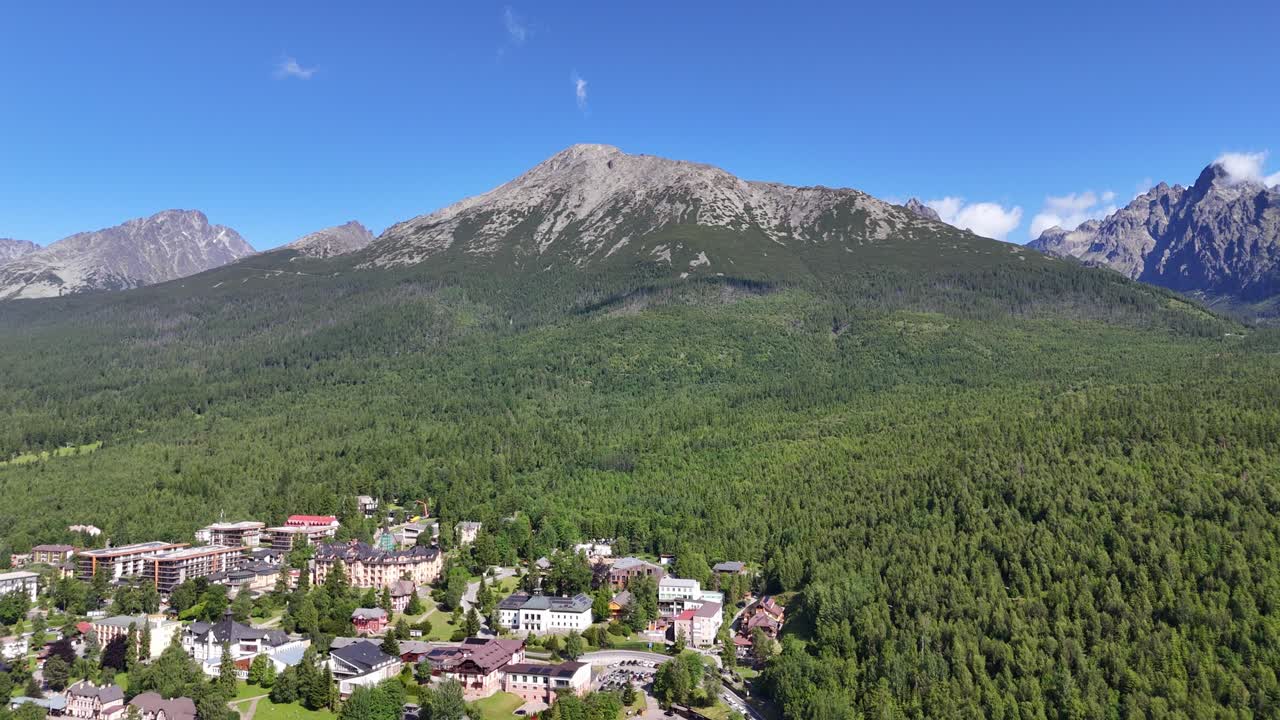 Drone captures Starý Smokovec in the High Tatras, Slovakia. Panoramic views of mountain landscapes, lush forests, and blue skies in summer light