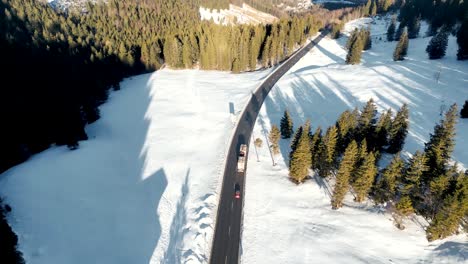 aerial drone footage: lorry truck transporting huge tree trunks over snowy mountain pass in bavarian alps, germany, forestry industry scene exporting commercial goods