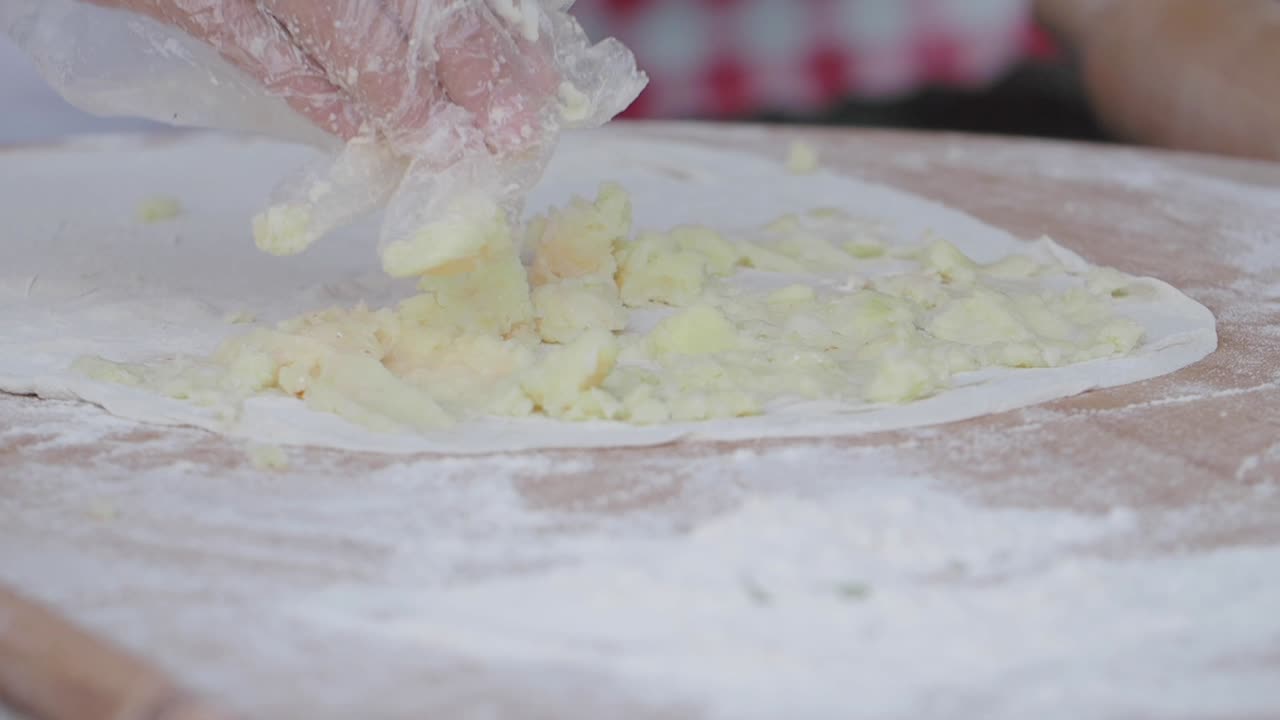 Mani che stendono ripieno di patate su pasta fresca per focaccia