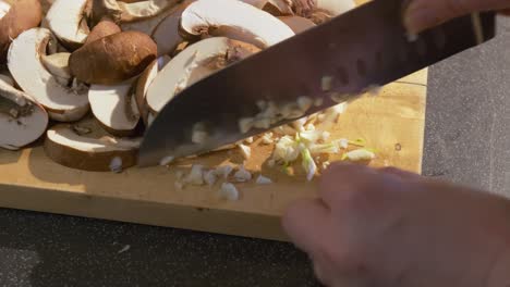 Close-up-of-garlic-and-fresh-mushrooms-being-sliced-by-a-woman-hand-preparing-a-healthy-recipe