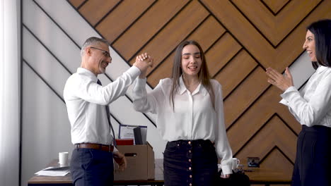 los compañeros de trabajo felices felicitan a la joven por dejar la empresa, la abrazan y se despiden mientras ella sale de la habitación