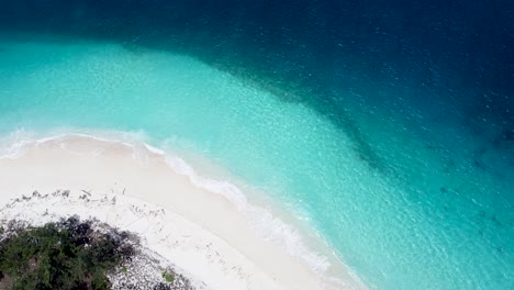 Mit-Blick-Auf-Eine-Atemberaubende-Abgelegene-Tropische-Insel-Mit-Natürlichen-Erdtönen,-Weißem-Sandstrand,-Flachem,-Kristallklarem-Wasser-Und-Tiefblauem-Ozean