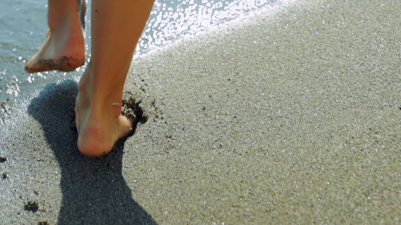 Piedi di donna che camminano sulla sabbia in spiaggia