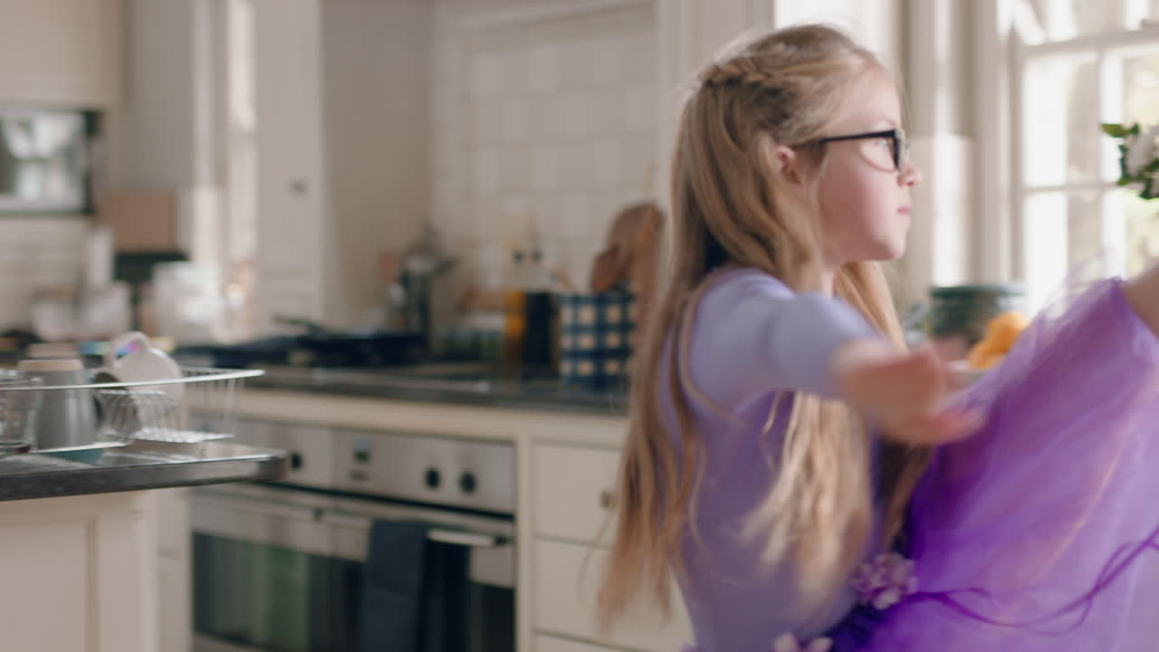 happy ballerina girl dancing in kitchen having fun practicing ballet dance moves wearing purple tutu at home