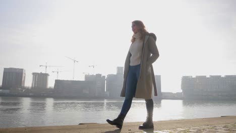 confident stylish woman poses and walks along a pier, silhouette by the sun