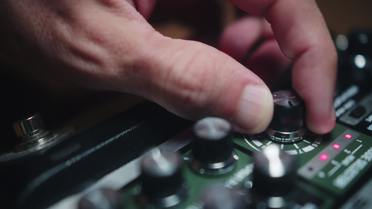 Close-up of a hand adjusting a knob on a guitar effects pedal