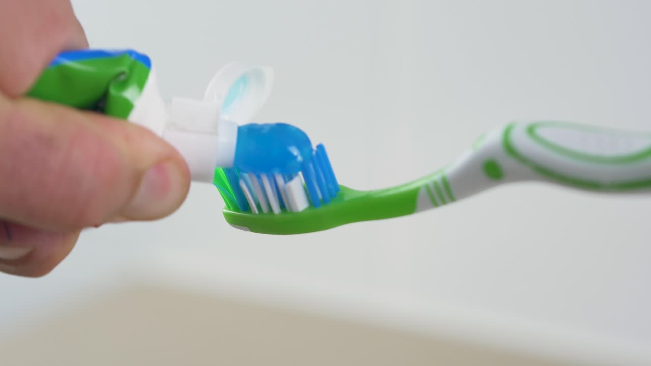primer plano de cámara lenta de pasta de dientes apretado en el cepillo de dientes gel dental limpieza higiene personal salud baño oral 4k