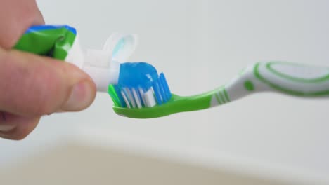 close-up slow motion shot of toothpaste squeeze onto toothbrush dental gel cleaning personal hygiene health oral bathroom 4k