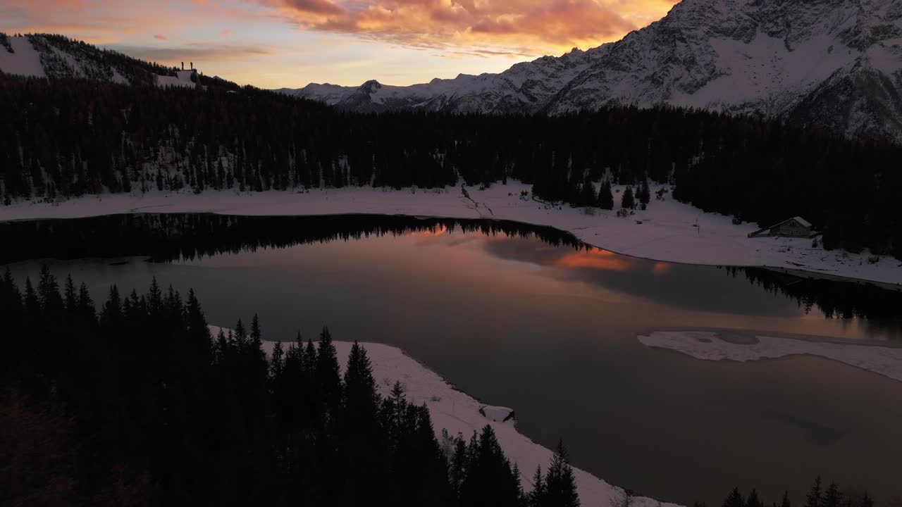 Veduta aerea del Lago di Palù in inverno al tramonto, Valmalenco della Valtellina in Italia, ripresa con drone in avanzamento