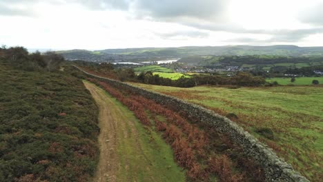 Sunbeams-moving-across-overcast-British-agricultural-rural-village-countryside-morning-aerial-low-push-in-view