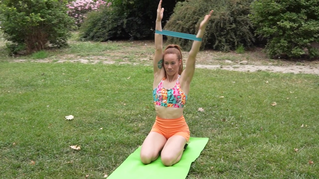 Mulher praticando yoga ao ar livre com uma faixa de resistência, focando no equilíbrio e na flexibilidade na natureza.
