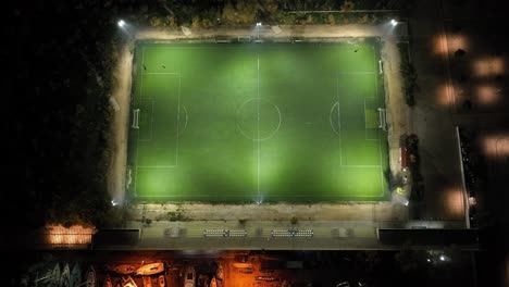 drone footage flying away from an illuminated soccer field at night