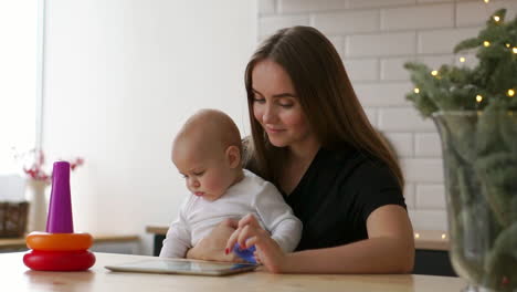familia, tecnología y concepto de maternidad - madre joven feliz y sonriente con un bebé pequeño y una tableta en casa