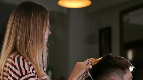 close-up, master hairdresser does hairstyle and style with scissors and comb. concept barbershop.