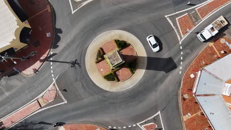 overhead drone footage captures cars, trucks, and buses moving through a sunlit roundabout in coonabarabran, new south wales, with clear shadows and urban surroundings