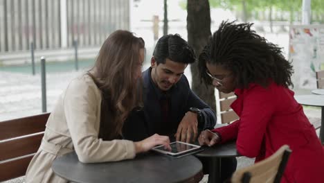 mujer afroamericana mostrando fotos en una tableta a una joven pareja