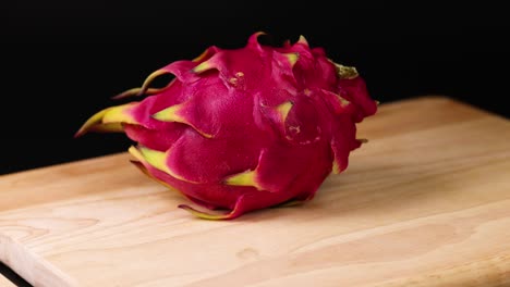 hand spins dragon fruit on a wooden board