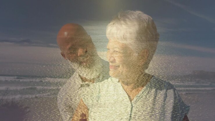 Retired couple standing at beach, overlay building and revealing man behind woman, reminiscing