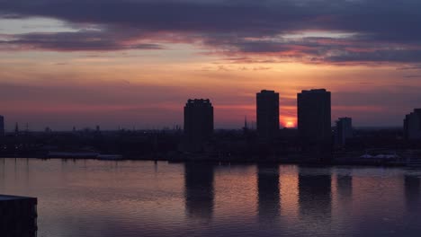 silhouette of high-rise buildings during sunset with reflections in delaware river - wide static