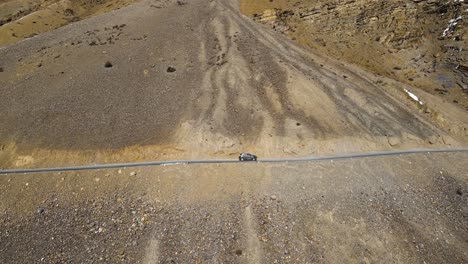 aerial drone following shot of a car passing sand mountain in spiti valley, himachal pradesh, india