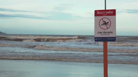 no swimming red warning sign on beach in