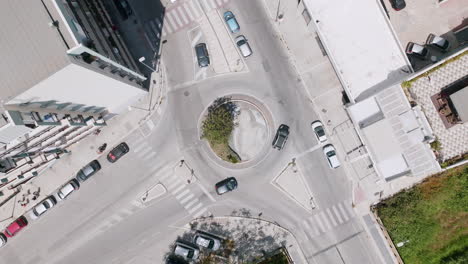 imágenes aéreas ascendentes rápidas de una rotonda en los suburbios de bari, italia, con autos moviéndose a su alrededor