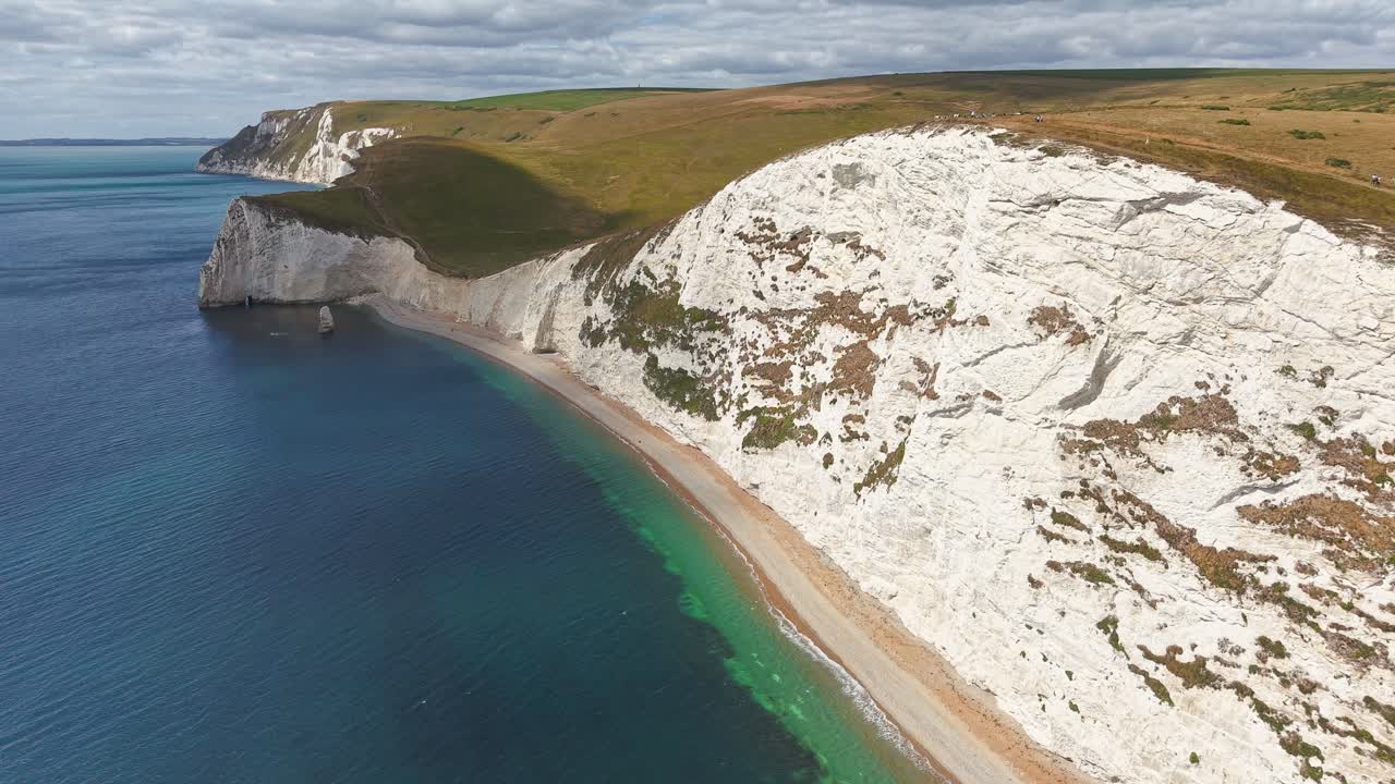 People walking the South West Coastal Path along dramatic white cliffs in summer