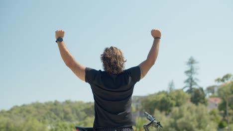 back view of athlete with disability raising hands up in park