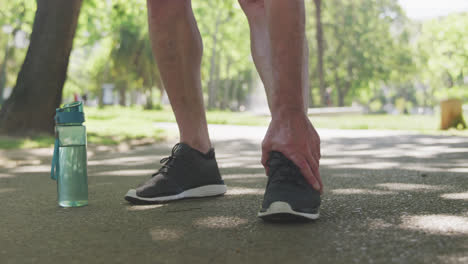 Low-section-of-man-holding-his-leg-in-the-park