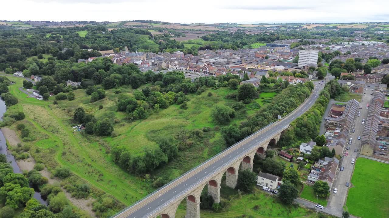 Aerial View of a Stone Viaduct Leading into a Green Valley and Town