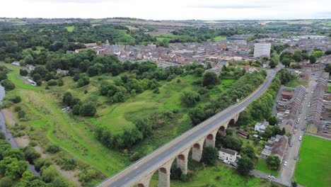 aerial view of a stone viaduct leading into a green valley and town