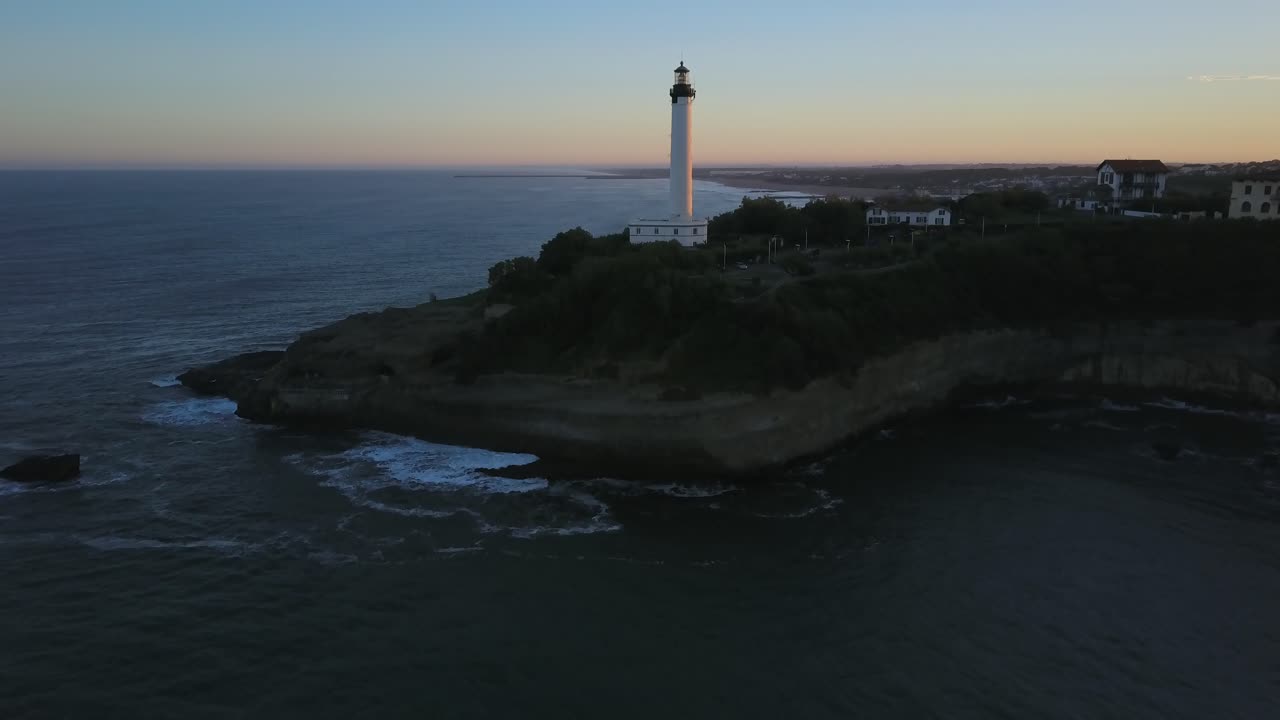 drone volando hacia el faro de biarritz al atardecer, francia