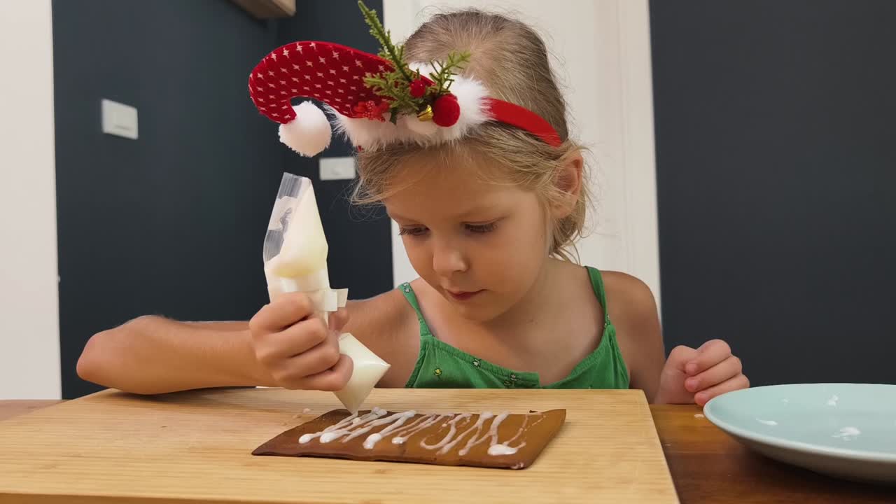 una niña decorando una casa de pan de jengibre