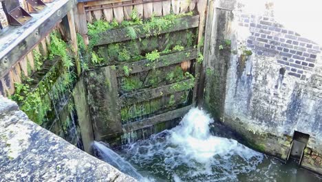 Vista-De-Cerca-De-Las-Compuertas-De-Esclusa-Que-Pierden-Agua-En-Un-Canal-A-Medida-Que-Baja-El-Nivel-Del-Agua