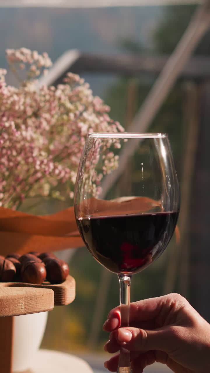Couple takes glasses of wine from snack tray. Man and woman clink glasses in celebration of honeymoon in glamping cottage surrounded by forest