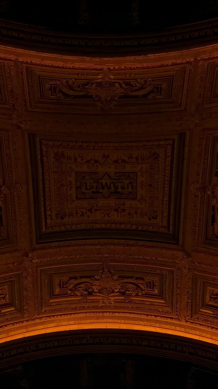Vertical video: Camera tilting revealing coffered ceiling and warm lit arch at hall, focusing panel